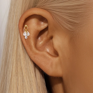Macro view of gold s925 silver stud earring with three sparkling teardrop zircon pendants