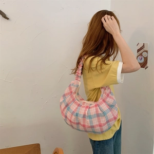 Rear view of a model wearing a pink and blue checkered crescent bag with ruffled straps
