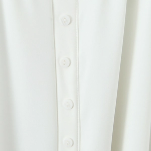 Elegant white halter neck dress with close-up detail of premium woven fabric and buttons