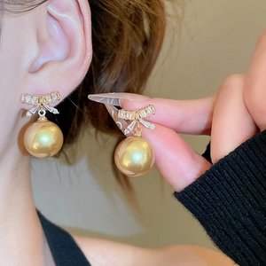 Detail showing bowknot earrings with zircon and large champagne pearls on a model