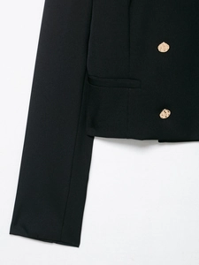 Dettaglio del blazer nero con bottoni dorati goffrati e tasca laterale a patta