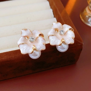 Gros plan de boucles d'oreilles fleurs en émail rose avec bords dorés et perles