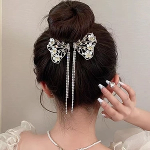 Dettaglio della clip per capelli a farfalla dorata con fiori di giglio e nappe di strass