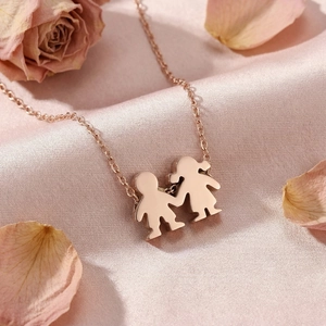 Close-up of rose gold couple pendant on pink silk with decorative dried roses