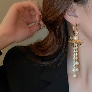 Detail of elegant gold tassel earrings with pearls and zircon on a model side profile