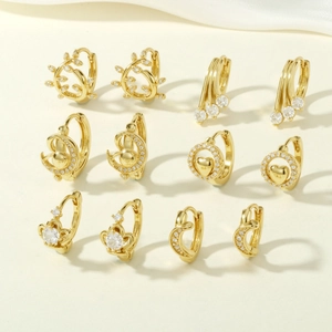 Set of six gold hoop earrings with zircon moons, hearts, and sun charms on beige fabric