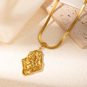 Close-up of golden snake chain necklace featuring a hammered irregular metal pendant