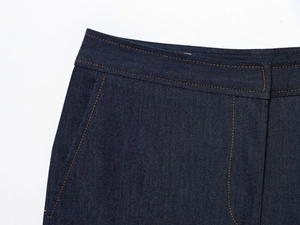 Gros plan détaillé du tissu denim indigo avec doubles coutures orange contrastantes