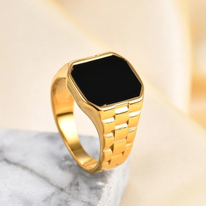 Detail of gold signet ring with square black stone and watchband texture on marble