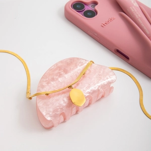 Detail of gold snake chain necklace with oval pendant and pink marble resin hair claw