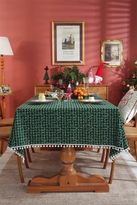 Detailed view of green and black plaid Christmas tablecloth with snowflake and white tassels