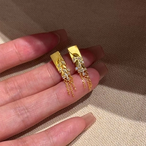 Détail de boucles d'oreilles épi de blé dorées avec zircons et pampilles à chaînes