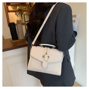Detail of white lychee leather handbag with metal buckle closure and detachable strap
