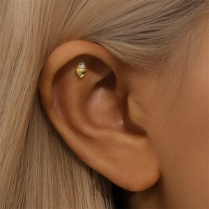 Macro shot of gold heart-shaped helix stud earring with clear zircon on ear bone
