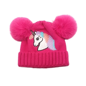 Détail de la broderie licorne et des deux pompons sur le bonnet tricoté rose