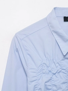 Gros plan du col de chemise en popeline bleu clair avec détails plissés raffinés