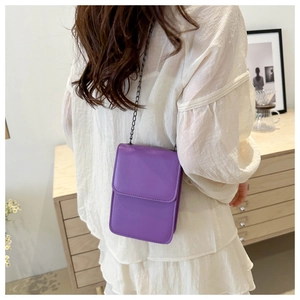 Rear view of a minimalist purple crossbody bag with chain strap on a model