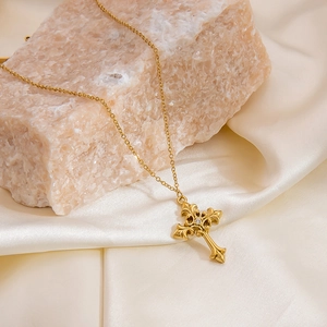 Détail macro d'un pendentif croix vintage gravé en or avec zircon sur pierre