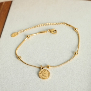 Gold snake chain bracelet featuring five beads and a vintage portrait coin pendant