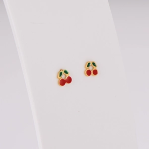 Close-up of golden cherry stud earrings with red and green enamel on a white stand