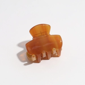 Detailed close-up of glossy amber leopard print hair claw clip with marble texture