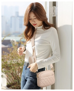 Detail of beige quilted crossbody bag with matching wide strap and round coin purse accessory