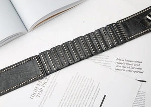 Close-up of a black punk leather waist belt with rows of square metal rivet studs