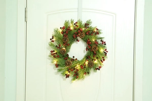 Close-up of a Christmas wreath with pine needles, red berries, cones, and warm LED lights