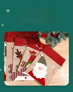 Assorted Christmas drawstring burlap gift bags with Santa and reindeer motifs on wood