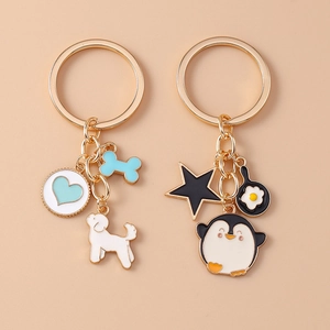 Detail of enamel dog and penguin keychains with gold metal star and bone charms