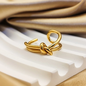 Detailed view of gold knot ring on white wavy stand with silk satin background