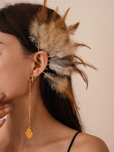 Λεπτομέρεια από boho χρυσό σκουλαρίκι αυτιού με φτερό ρητίνης και μακριά αλυσίδα με πέτρα