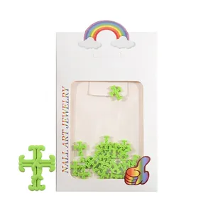 Nahaufnahme von neongrünen 3D-Nagel-Charms in Kreuzform mit kleiner Schmuckbox