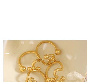 Detail of gold-plated twisted hoop earrings in a ceramic dish with white ribbon