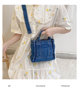 Detailed view of blue denim handbag with front pocket and detachable shoulder strap