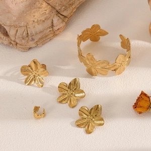 Golden geometric flower jewelry set including bracelet, earrings and ring on a textured base