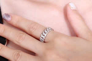 Macro detail of silver-toned Cuban link ring with pavé set zircon stones on finger