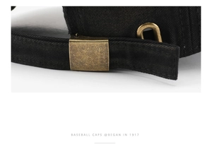Close-up of the adjustable bronze metal buckle on a distressed black cotton baseball cap