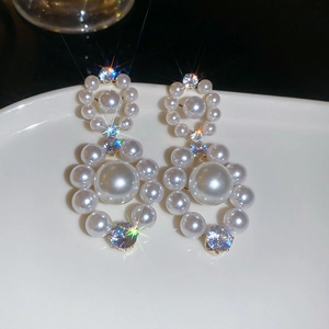 Détail macro de boucles d'oreilles perles avec zircons brillants en design double cercle