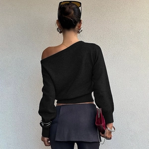 Détail d'un haut noir en maille à épaule dénudée avec coupe asymétrique et texture côtelée
