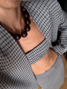 Détail de l'ensemble blazer en tweed à motif pied-de-poule bleu et collier de perles