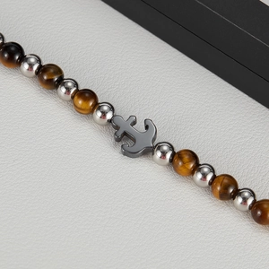 Detailed close-up of tiger eye stone beads and silver anchor pendant on a men bracelet