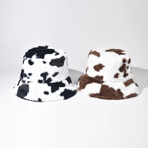 Detailed comparison of plush faux fur bucket hats in black and brown cow print patterns