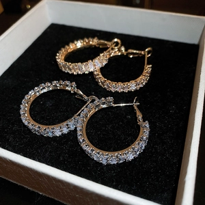 Close-up of gold and silver hoop earrings with pave-set rectangular cubic zirconia stones