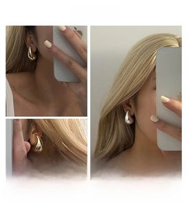 Macro detail of polished gold and silver teardrop earrings with a mirror finish