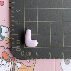 Macro view of light purple resin letter L accessory on a cm scale cutting mat