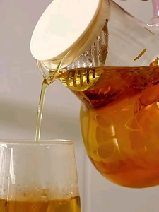 Close-up of heart glass teapot pouring tea featuring a built-in filter and white lid