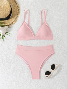 Pink ribbed bikini set with triangle top and high waist bottom on beach accessories background