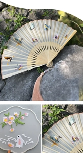 Macro detail of silk folding fan with butterfly embroidery and bamboo ribs with tassels