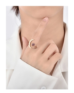 Close-up of golden crescent moon ring with claw-set purple gemstone on model finger